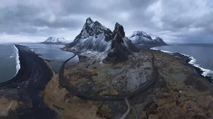 Framed Print : Aerial view of asphalt road going between snowy mountain and blue ocean under cloudy sky in Eystrahorn Framed Print : Aerial view of asphalt road going between snowy mountain and blue ocean under cloudy sky in Eystrahorn