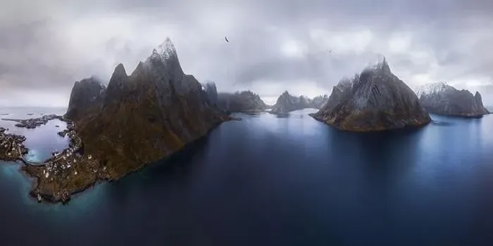 Framed Print : Aerial view of calm water of sea washing island with rocky formations under cloudy sky with small village in Rein Framed Print : Aerial view of calm water of sea washing island with rocky formations under cloudy sky with small village in Rein
