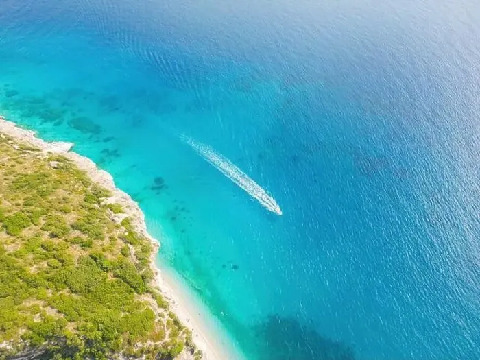 Framed Print : Aerial view of a clear blue sea. A boat leaving a white trail and a sunlit shoreline Framed Print : Aerial view of a clear blue sea. A boat leaving a white trail and a sunlit shoreline