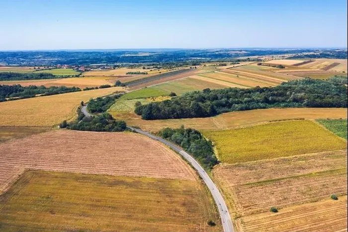 Framed Print : Aerial view of a country road amid fields against blue clear sky Framed Print : Aerial view of a country road amid fields against blue clear sky