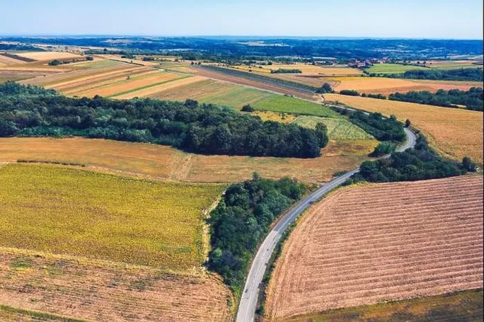 Framed Print : Aerial view of a country road amid fields against blue clear sky Framed Print : Aerial view of a country road amid fields against blue clear sky
