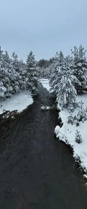 Framed Print : An aerial view of a frozen river flowing through snow-covered forests on a cloudy sunset sky background Framed Print : An aerial view of a frozen river flowing through snow-covered forests on a cloudy sunset sky background