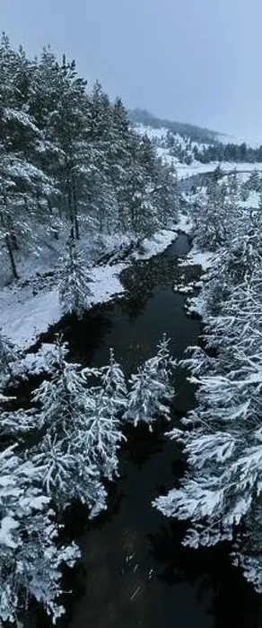 Framed Print : An aerial view of a frozen river flowing through snow-covered forests on a cloudy sunset sky background