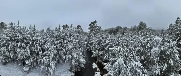 Framed Print : An aerial view of a frozen river flowing through snow-covered forests on a cloudy sunset sky background Framed Print : An aerial view of a frozen river flowing through snow-covered forests on a cloudy sunset sky background