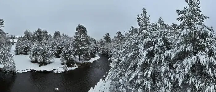 Framed Print : An aerial view of a frozen river flowing through snow-covered forests on a cloudy sunset sky background Framed Print : An aerial view of a frozen river flowing through snow-covered forests on a cloudy sunset sky background
