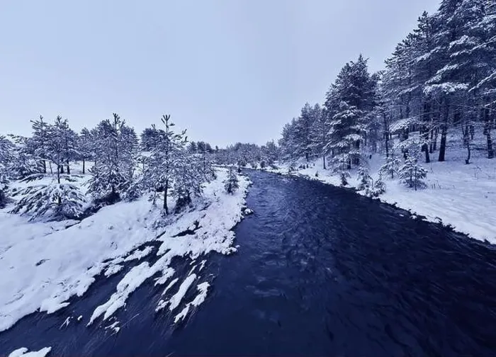 Framed Print : An aerial view of a frozen river flowing through snow-covered forests on a cloudy sunset sky background Framed Print : An aerial view of a frozen river flowing through snow-covered forests on a cloudy sunset sky background