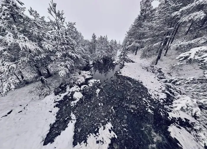 Framed Print : An aerial view of a frozen river flowing through snow-covered forests on a cloudy sunset sky background Framed Print : An aerial view of a frozen river flowing through snow-covered forests on a cloudy sunset sky background