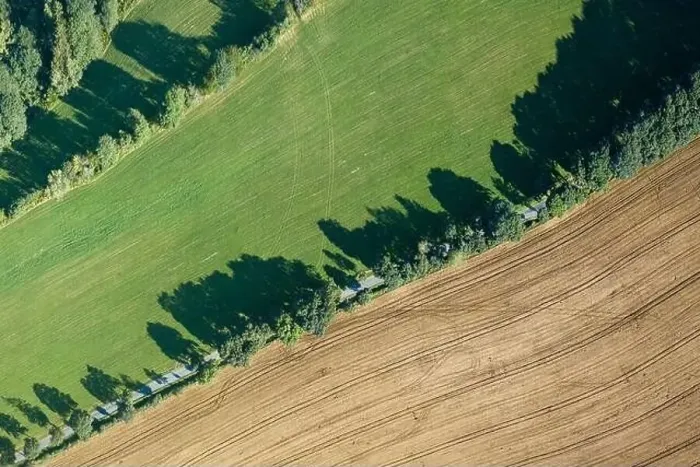 Framed Print : Aerial view of a green agricultural field with a rural road passing through it. Summer time, sunny day in landscape Framed Print : Aerial view of a green agricultural field with a rural road passing through it. Summer time, sunny day in landscape