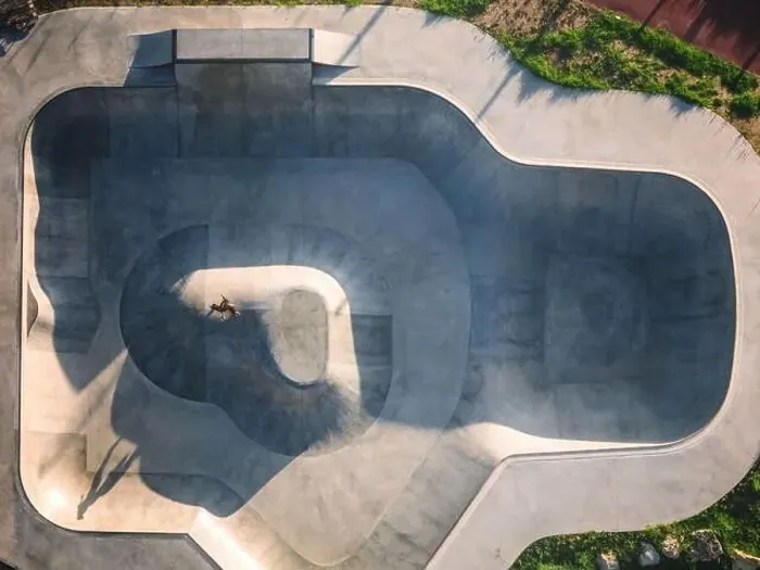 Framed Print : Aerial view of a modern skateboard park featuring diverse ramps and a skater performing tricks in the afternoon light Framed Print : Aerial view of a modern skateboard park featuring diverse ramps and a skater performing tricks in the afternoon light