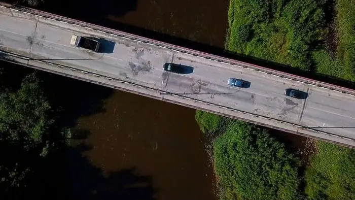 Framed Print : Aerial top view of a narrow bridge above brown dirty river. Clip. Green shores with bushes and driving cars Framed Print : Aerial top view of a narrow bridge above brown dirty river. Clip. Green shores with bushes and driving cars