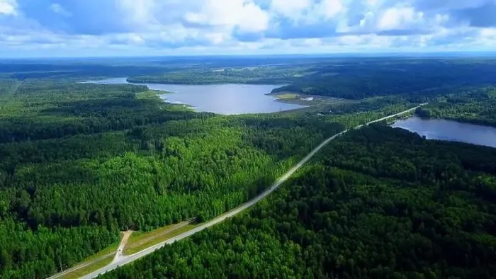 Framed Print : Aerial view of a narrow road becoming a bridge above the long river. Clip. Green forest and blue cloudy sky Framed Print : Aerial view of a narrow road becoming a bridge above the long river. Clip. Green forest and blue cloudy sky