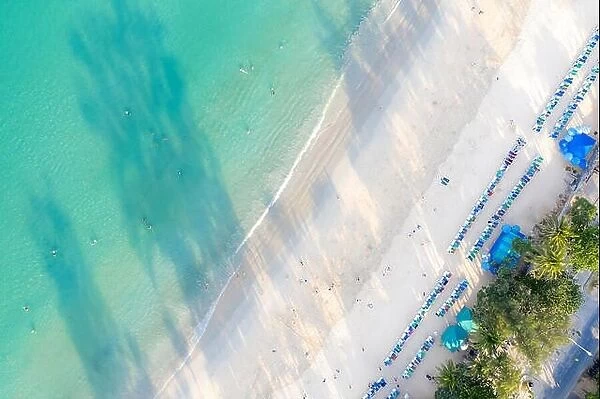 Aerial view of people swimming on the pink swim ring in the transparent turquoise sea in Phuket, Thailand