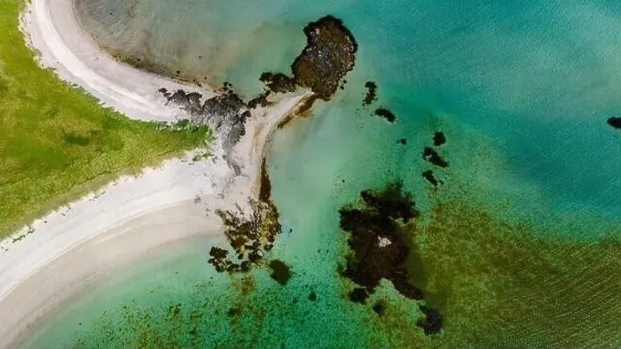 Framed Print : An aerial view of a pristine beach curving around a rocky outcropping Framed Print : An aerial view of a pristine beach curving around a rocky outcropping