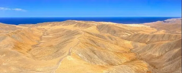 Framed Print : Aerial view of empty road crossing the desert mountains towards the blue Atlantic Ocean Framed Print : Aerial view of empty road crossing the desert mountains towards the blue Atlantic Ocean