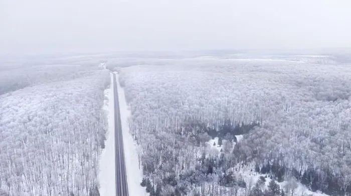 Framed Print : Aerial view of a road cutting through a snowy forest on a cloudy day Framed Print : Aerial view of a road cutting through a snowy forest on a cloudy day