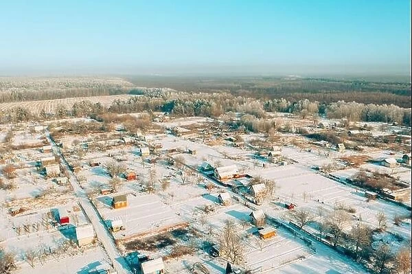 Aerial view of snow-covered vegetable gardens in country village. Skyline in winter day. Bird's-eye view oof small town, village cityscape skyline in