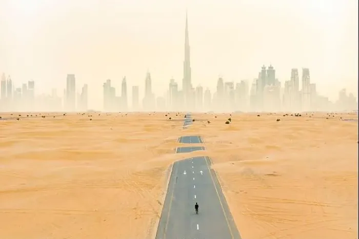 Framed Print : Aerial view of an unidentified person walking on a deserted road covered by sand dunes with the Dubai Skyline in Framed Print : Aerial view of an unidentified person walking on a deserted road covered by sand dunes with the Dubai Skyline in