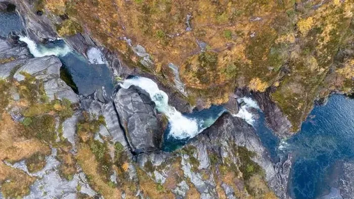 Framed Print : Aerial view of a waterfall cascading through rocky terrain surrounded by autumn foliage Framed Print : Aerial view of a waterfall cascading through rocky terrain surrounded by autumn foliage