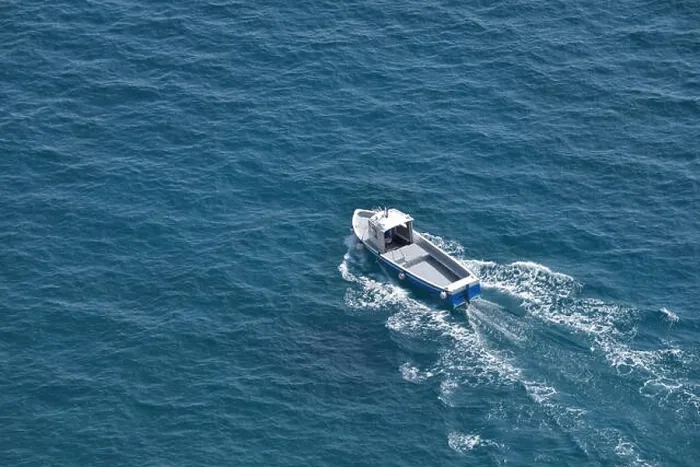 Framed Print : Aerial view of a white fishing boat on a blue clear sea water
