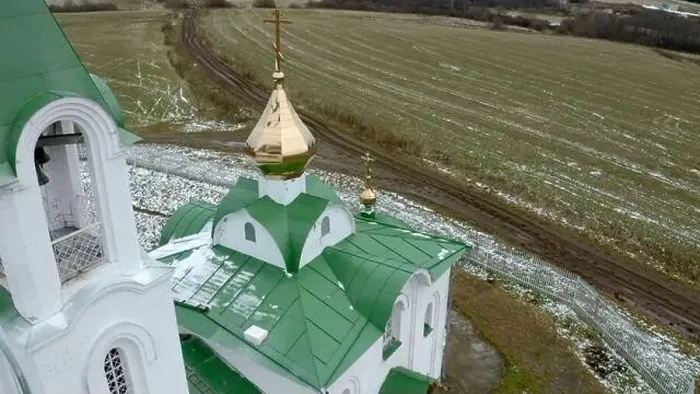 Framed Print : Aerial view of a white and green church with a golden cross and bell. Clip. Green field covered by snow Framed Print : Aerial view of a white and green church with a golden cross and bell. Clip. Green field covered by snow