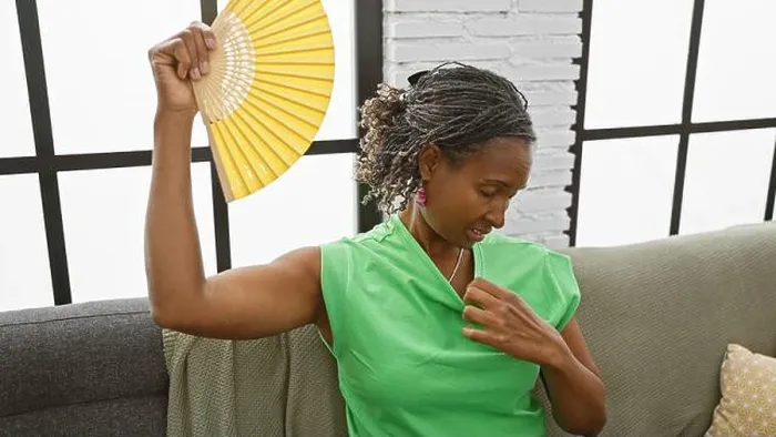 Framed Print : African american woman fanning herself indoors, feeling hot despite the home's modern, bright interior Framed Print : African american woman fanning herself indoors, feeling hot despite the home's modern, bright interior