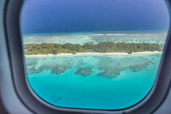 Airplane window with beautiful Maldives island view. Luxury summer holiday travel tourism background, view from airplane window. Atolls islands