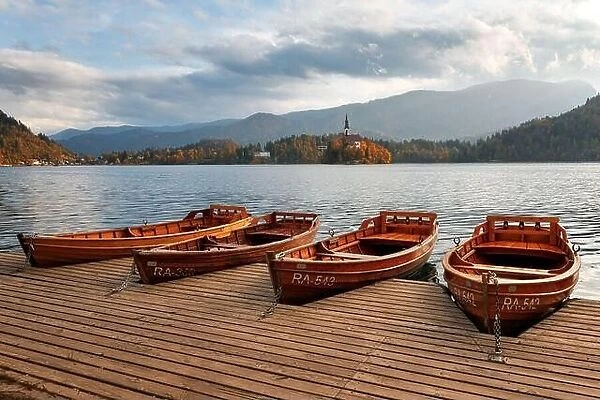 Amazing autumn view of Bled lake in Julian Alps, Slovenia. Wooden boat on city pier. Pilgrimage church of the Assumption of Maria on a foreground