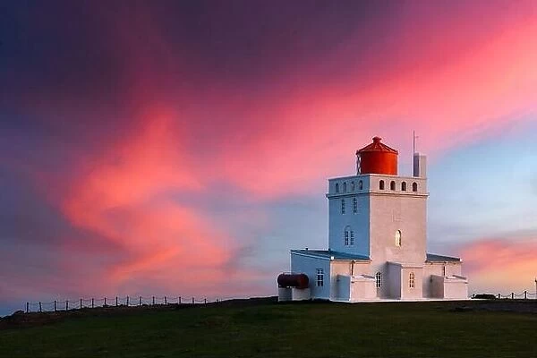 Amazing evening view of Dyrholaey Lighthouse at Cape Dyrholaey, south coast of Iceland. Great purple sunset glowing on background