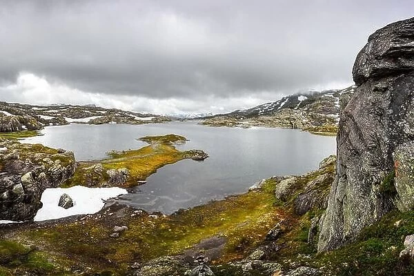 Amazing norwegian landscape with clear lake and snowy mountains