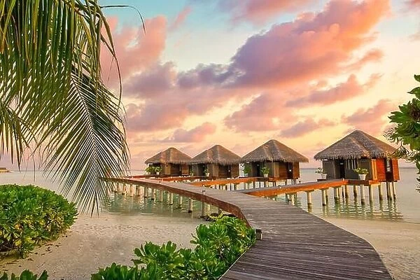 Amazing sunset panorama at Maldives. Luxury resort villas seascape with soft led lights under colorful sky. Beautiful twilight sky and colorful clouds