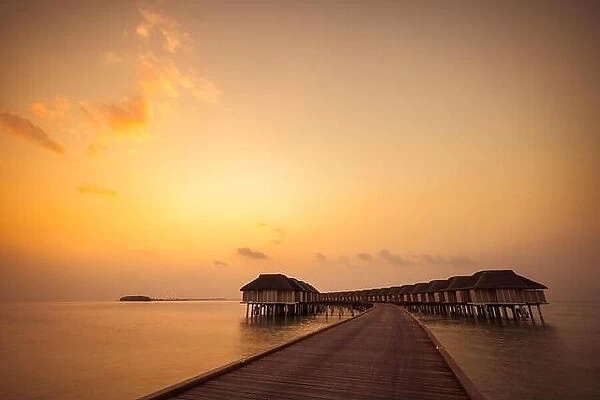 Amazing sunset sky and reflection on calm sea, Maldives beach landscape of luxury over water bungalows. Exotic scenery of summer vacation and holiday