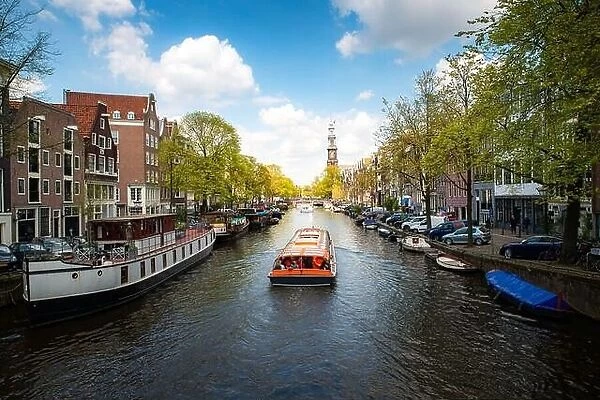 Amsterdam canal with cruise ship with Netherlands traditional house in Amsterdam, Netherlands. Landscape and culture travel, or historical building an