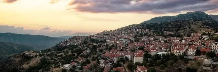 Framed Print : Arachova Greece mountain town aerial panoramic view. Traditional houses and stone tower clock cloudy sky at sunset