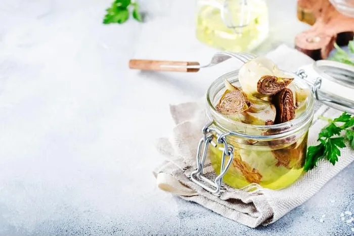 Framed Print : Artichokes in olive oil in jar with lemon and herbs on gray kitchen table background, selective focus Framed Print : Artichokes in olive oil in jar with lemon and herbs on gray kitchen table background, selective focus