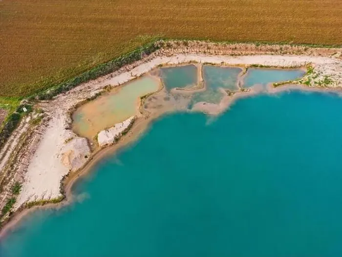 Framed Print : An artificial lake with turquoise water and several pools on the shore next to agricultural fields as an aerial view