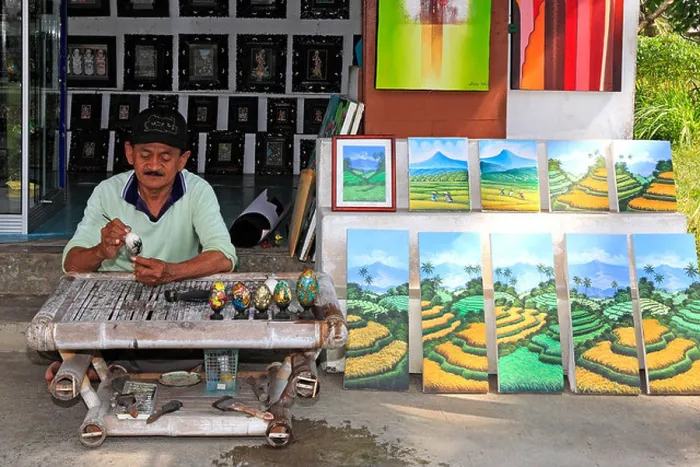 Framed Print : Artist Wayan Rana, painting eggs, outside his shop in Sebali Village, near Ubud. Bali, Indonesia. Model Released Framed Print : Artist Wayan Rana, painting eggs, outside his shop in Sebali Village, near Ubud. Bali, Indonesia. Model Released