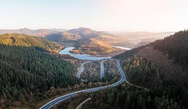 Autumn mountains panorama with mountain road serpentine, river and mixed forest. Aerial drone view. Landscape photography