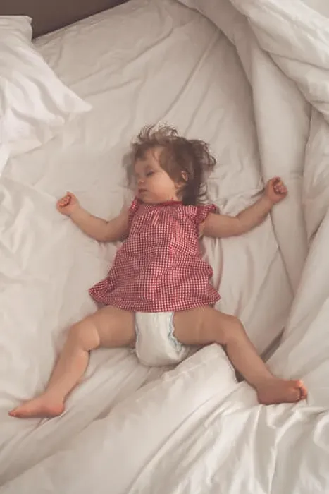 Framed Print : Baby girl sleeping on back with open arms and without pacifier in a bed with white sheets Framed Print : Baby girl sleeping on back with open arms and without pacifier in a bed with white sheets
