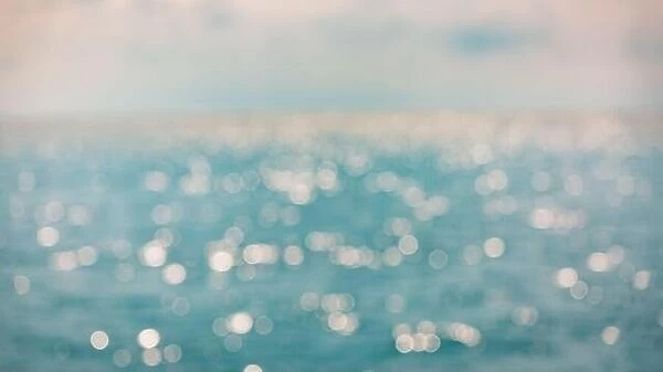 Background of blurred sunset beach and sea waves with bokeh lights. Artistic ocean blur