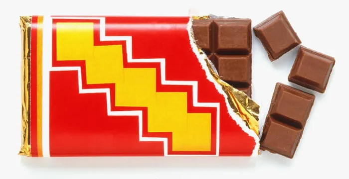 Framed Print : Bar of milk chocolate with one corner unwrapped and four squares broken off, close up