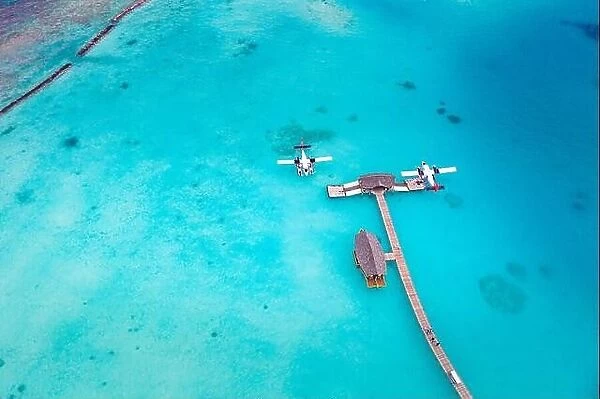 Beautiful aerial view of Maldives jetty seaplane top view with wooden boat Dhoni and tropical beach, jetty over wonderful blue sea. Luxury travel