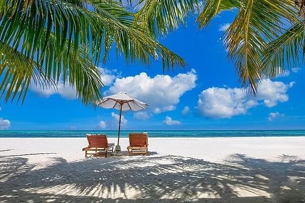 Beautiful tropical island scenery, two sun beds, loungers, umbrella under palm tree. White sand, sea view with horizon, idyllic blue sky, leisure