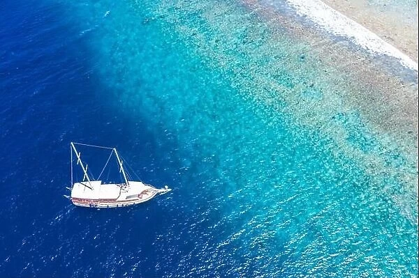 Beautiful turquoise ocean water boat top view aerial photo. Aerial view speed boat in the sea. Exotic sea lagoon, snorkel adventure, tropical ocean