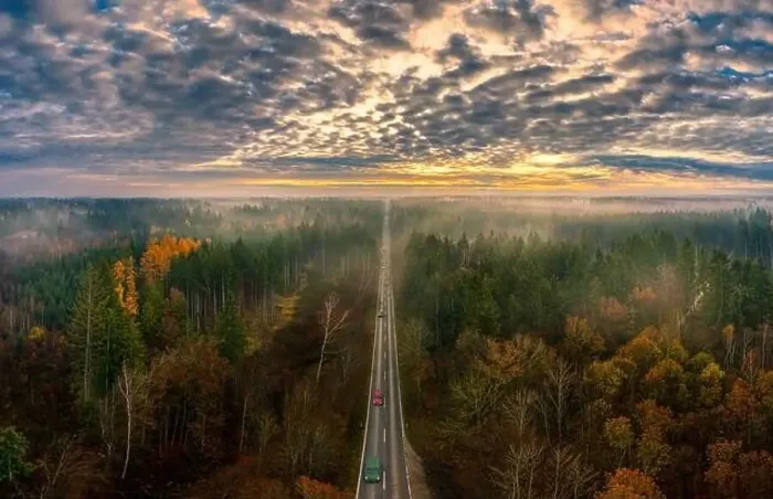 Framed Print : The beautiful view over a road framed by autumn colored trees with view to the mountains in background Framed Print : The beautiful view over a road framed by autumn colored trees with view to the mountains in background