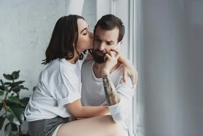 Framed Print : beautiful woman kissing man talking on smartphone at home Framed Print : beautiful woman kissing man talking on smartphone at home