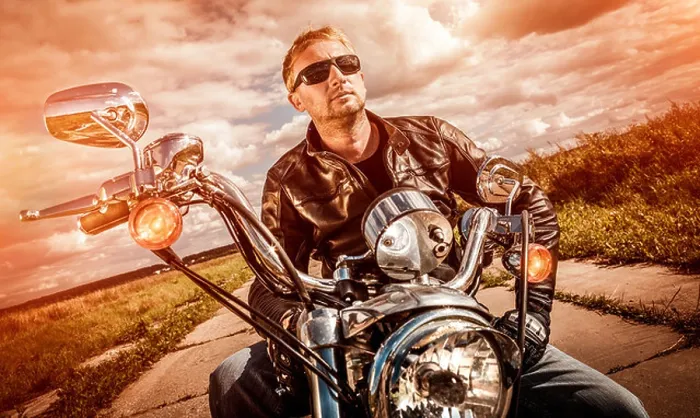 Framed Print : Biker man wearing a leather jacket and sunglasses sitting on his motorcycle looking at the sunset