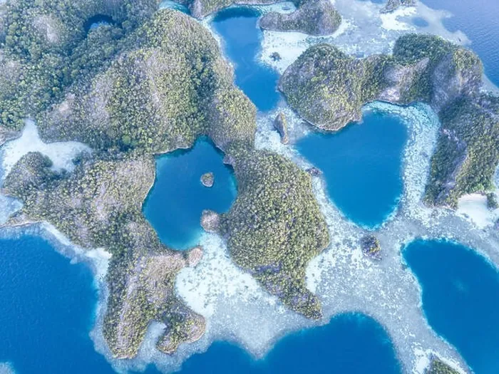 Framed Print : A bird's eye view shows dramatic limestone islands surrounding coral reefs in the peaceful, tropical seascape in Raja Ampat, Indonesia Framed Print : A bird's eye view shows dramatic limestone islands surrounding coral reefs in the peaceful, tropical seascape in Raja Ampat, Indonesia
