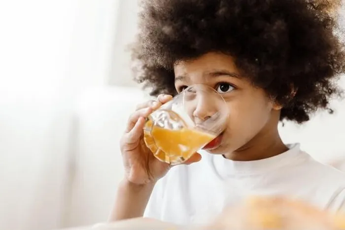 Framed Print : Black curly boy looking forward while drinking juice indoors Framed Print : Black curly boy looking forward while drinking juice indoors