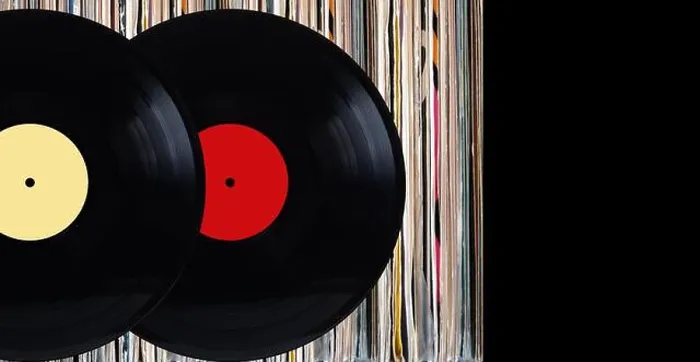 Framed Print : Two black vinyl records with color labels in front of shelf of many close standing vinyl discs in old color covers over Framed Print : Two black vinyl records with color labels in front of shelf of many close standing vinyl discs in old color covers over