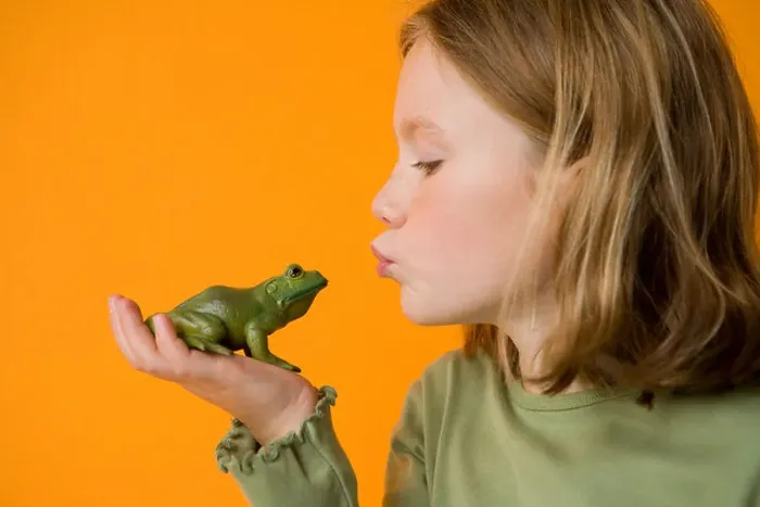Framed Print : blond girl kissing toy frog to make a wish